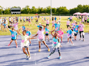 Girls on the Run participants gather with hands open to each other while they doing an activity