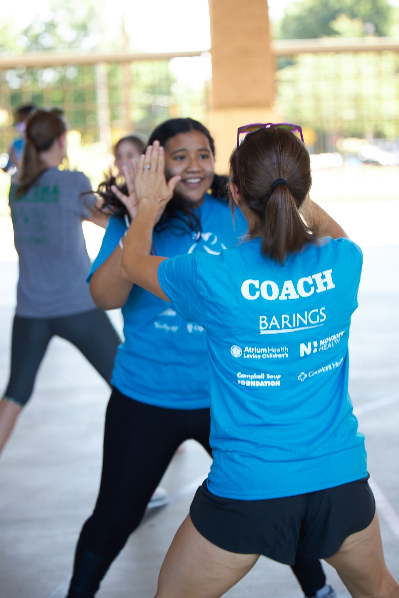 Two Girls on the Run participants smile at the camera while running at an outdoor practice in yellow shirts